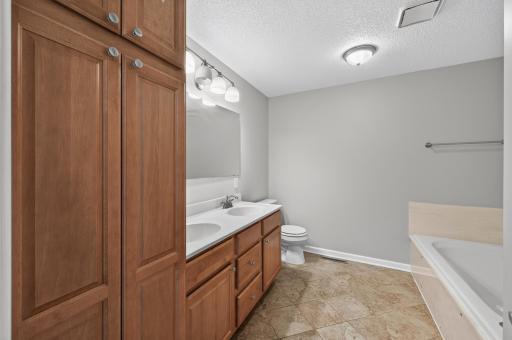 Upper-level full bath with dual-sink vanity, linen storage, and a soaking tub.