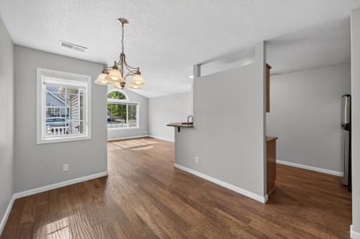 Bright dining area with hardwood floors and convenient access to both the kitchen and living room.