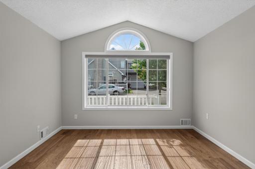 Large picture window and vaulted ceiling create a bright, welcoming atmosphere in the home's main gathering space.