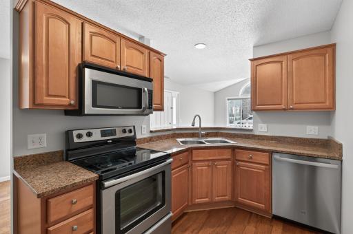 Functional kitchen featuring stainless steel appliances, abundant cabinetry, and a convenient breakfast bar overlooking the living room.