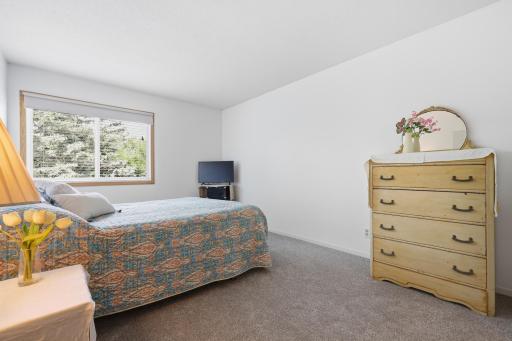 Wake up to natural light and a peaceful view in this inviting bedroom. The soft neutral tones, plush carpeting, and spacious layout create a warm and relaxing retreat—an ideal place to unwind at the end of the day and start each morning feeling right
