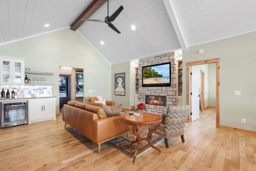 The inviting living room features a stunning handcrafted stone fireplace and a convenient beverage center, creating the perfect space for relaxing, entertaining, and enjoying the warmth and charm of lakeside living.