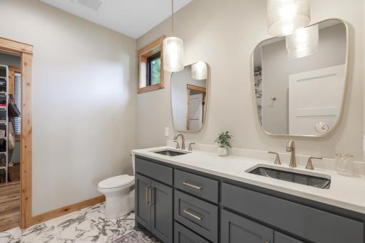 The primary bath features high-end cabinetry, elegant tile flooring, and dual sinks, blending luxury, style, and everyday functionality.