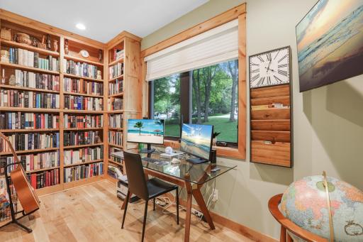 The study features an expansive built-in bookshelf and a large window overlooking the beautifully treed yard, creating a warm, inviting space for reading, working, or relaxing.