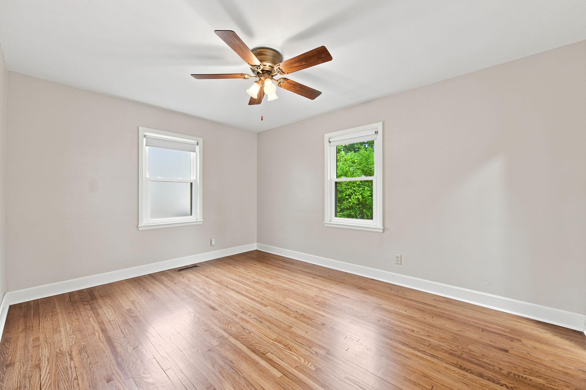 Generously sized primary BR with daylight from two sides and gleaming hardwood floors