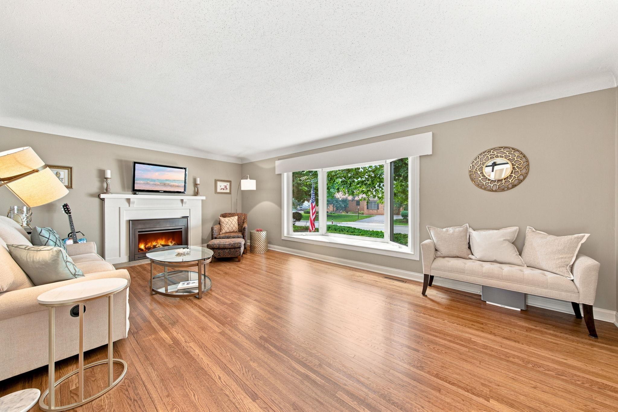 Spacious living room featuring an updated bay window with custom window treatments