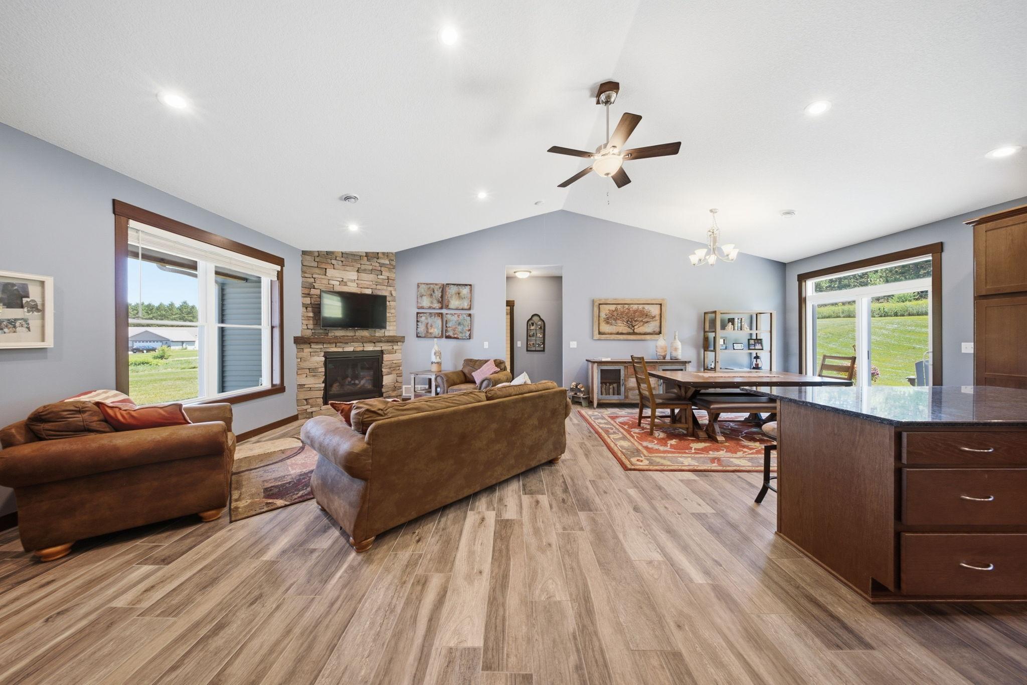 Open-concept main living area with vaulted ceilings, stone fireplace, and abundant natural light.