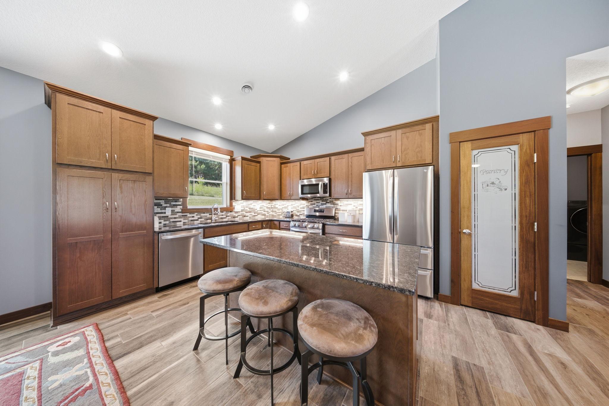 Well-appointed kitchen featuring granite countertops, center island, stainless steel appliances, and pantry.