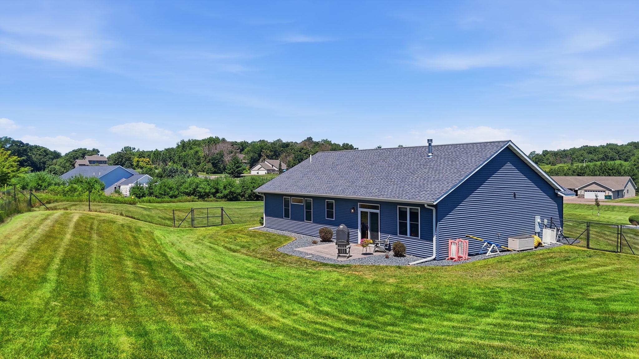 Beautifully maintained yard with open green space and a private backdrop of mature trees.