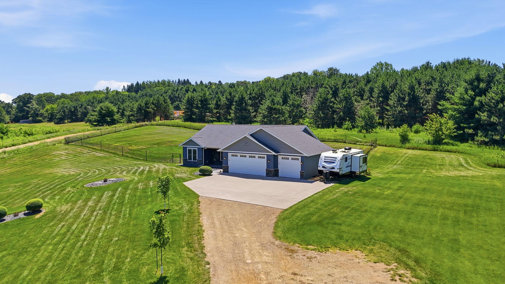 Quality-built home situated on a picturesque lot, open space, and a wooded backdrop.