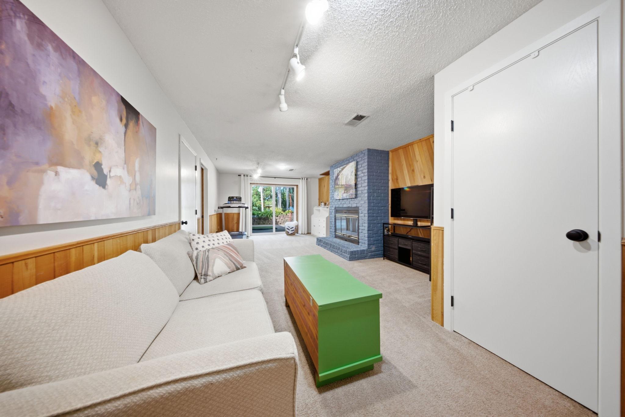 Lower-level family room featuring a cozy brick fireplace and walkout access.