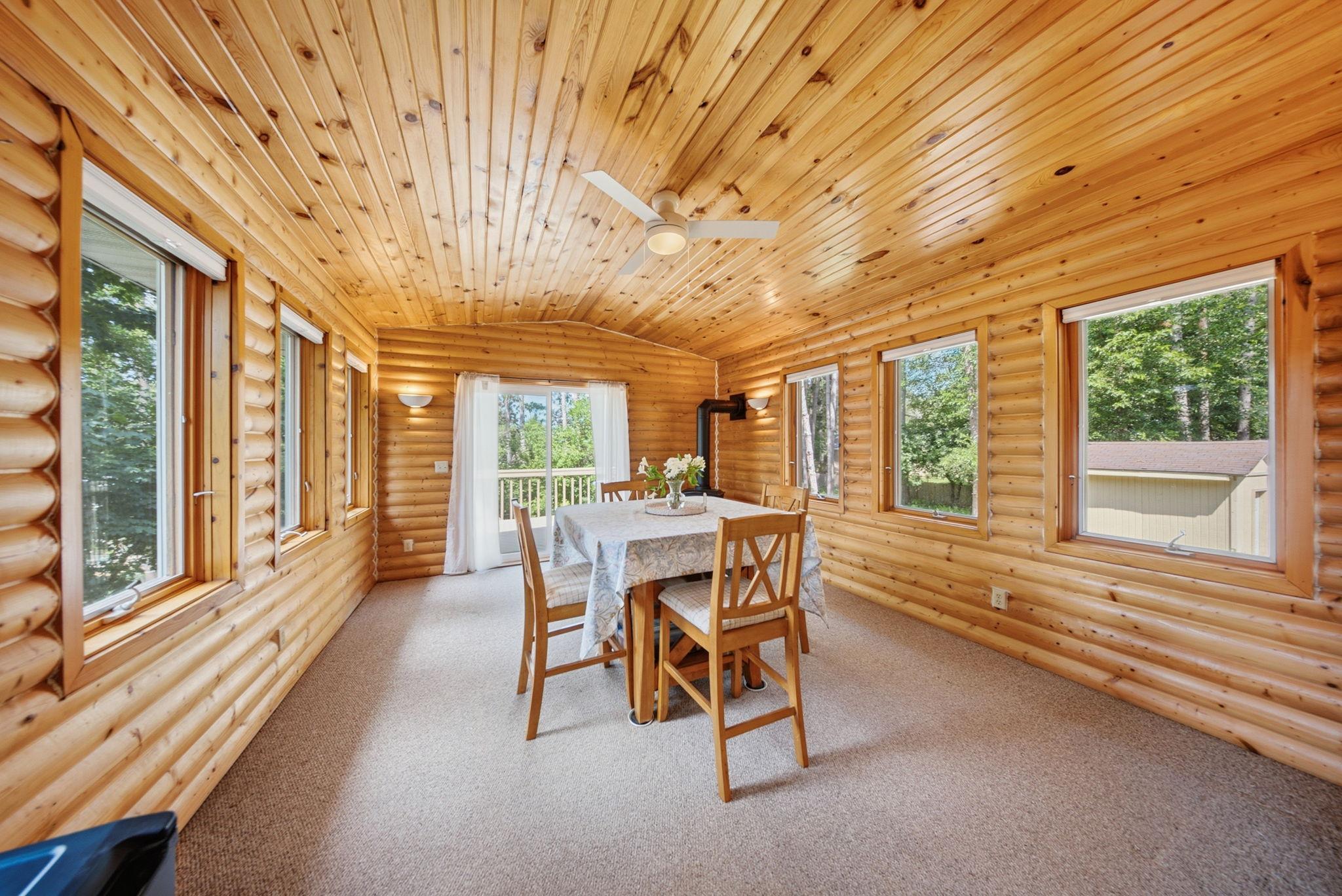 Warm and inviting four-season porch surrounded by windows and wooded views.