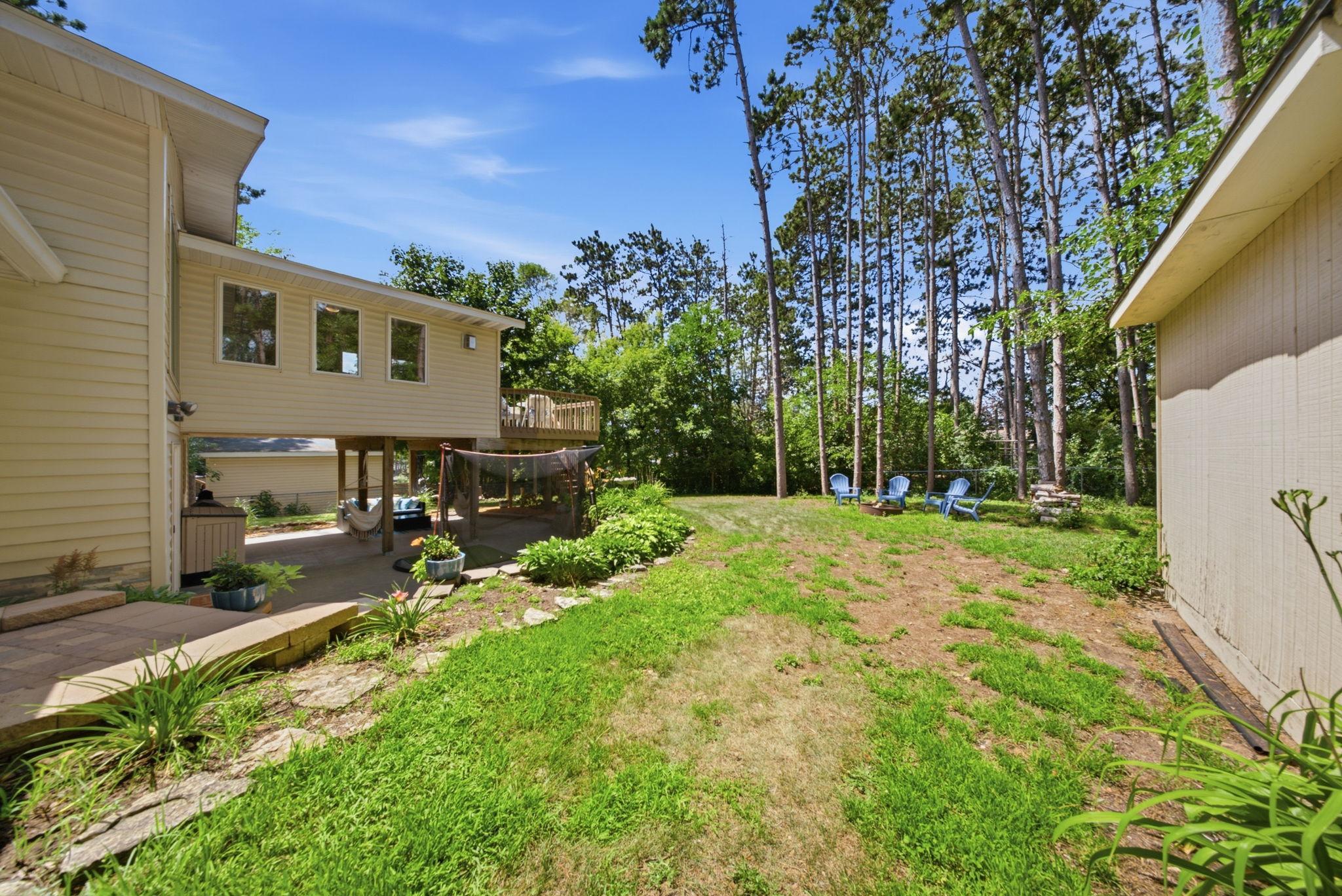 Private backyard featuring mature landscaping, multiple gathering spaces, and a storage shed.