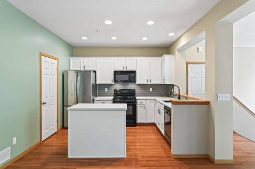 Updated kitchen featuring quartz countertops, white cabinetry, stainless steel appliances, and a center island.