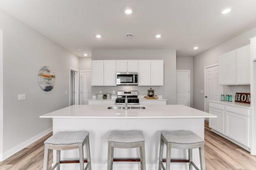 Look at this beautiful kitchen! Fantastic island with beautiful quartz countertops! *Photo is of a model home. Cabinets in the property for sale are grey.