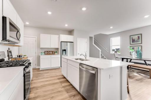 A fantastic place to entertain! The dining and living rooms flow seamlessly into the kitchen area! *Photo is of a model home. Cabinets in the property for sale are grey.