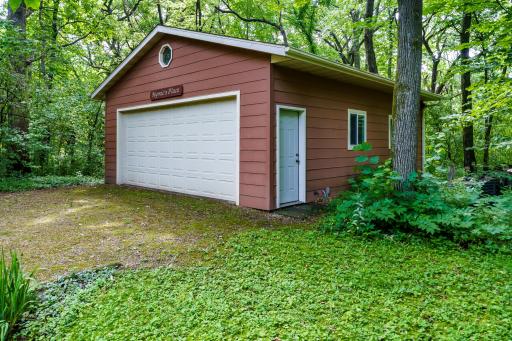 Spacious 24x29 detached garage featuring a wide overhead door, convenient side and back service doors, and matching siding that blends perfectly.