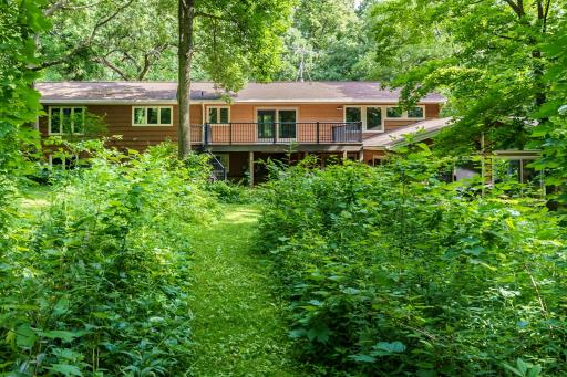 AnA large elevated maintenance-free deck overlooks a serene backyard retreat, surrounded by mature trees, privacy, and cleared paths.