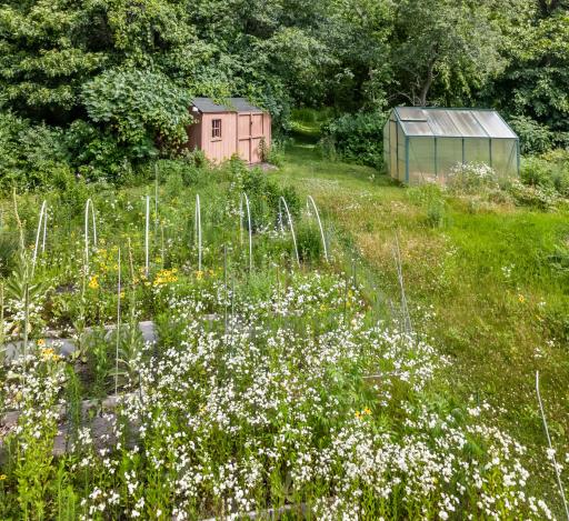 A gardener's dream! Trails lead to the back of the property, revealing an established garden space equipped with a greenhouse, storage shed, and convenient water lines already run to the site.