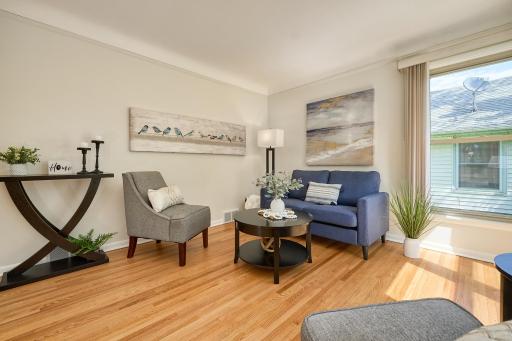 Living room with cove ceiling, original hardwood floors, and large vinyl windows.