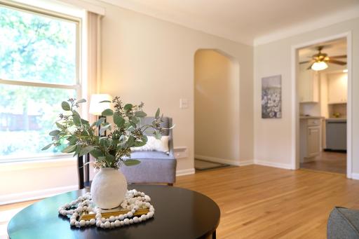 The living room has a cove ceiling, original hardwood flooring, & arched entryway.
