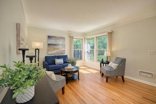 The living room has large windows, a cove ceiling, original hardwood flooring, & arched entryway.