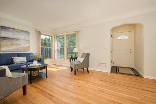 The living room has a cove ceiling, original hardwood flooring, & arched entryway.
