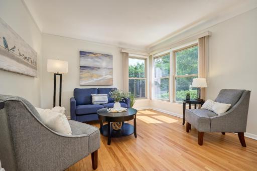 The living room has large windows, a cove ceiling, and original hardwood flooring.