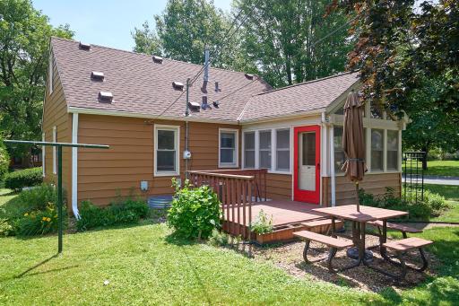 Wood deck off the vaulted 3-season porch surrounded by perennial flower beds. Roof and siding are new in 2024.