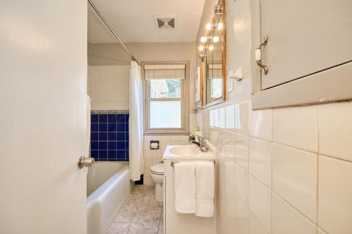 Main-floor full bath. The tub has beautiful tile surround. There's even a laundry chute.