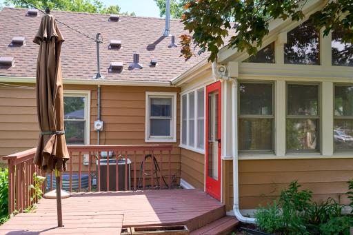 The vaulted three-season porch opens to a deck with stairs leading down to a charming patio, creating seamless indoor-outdoor living.