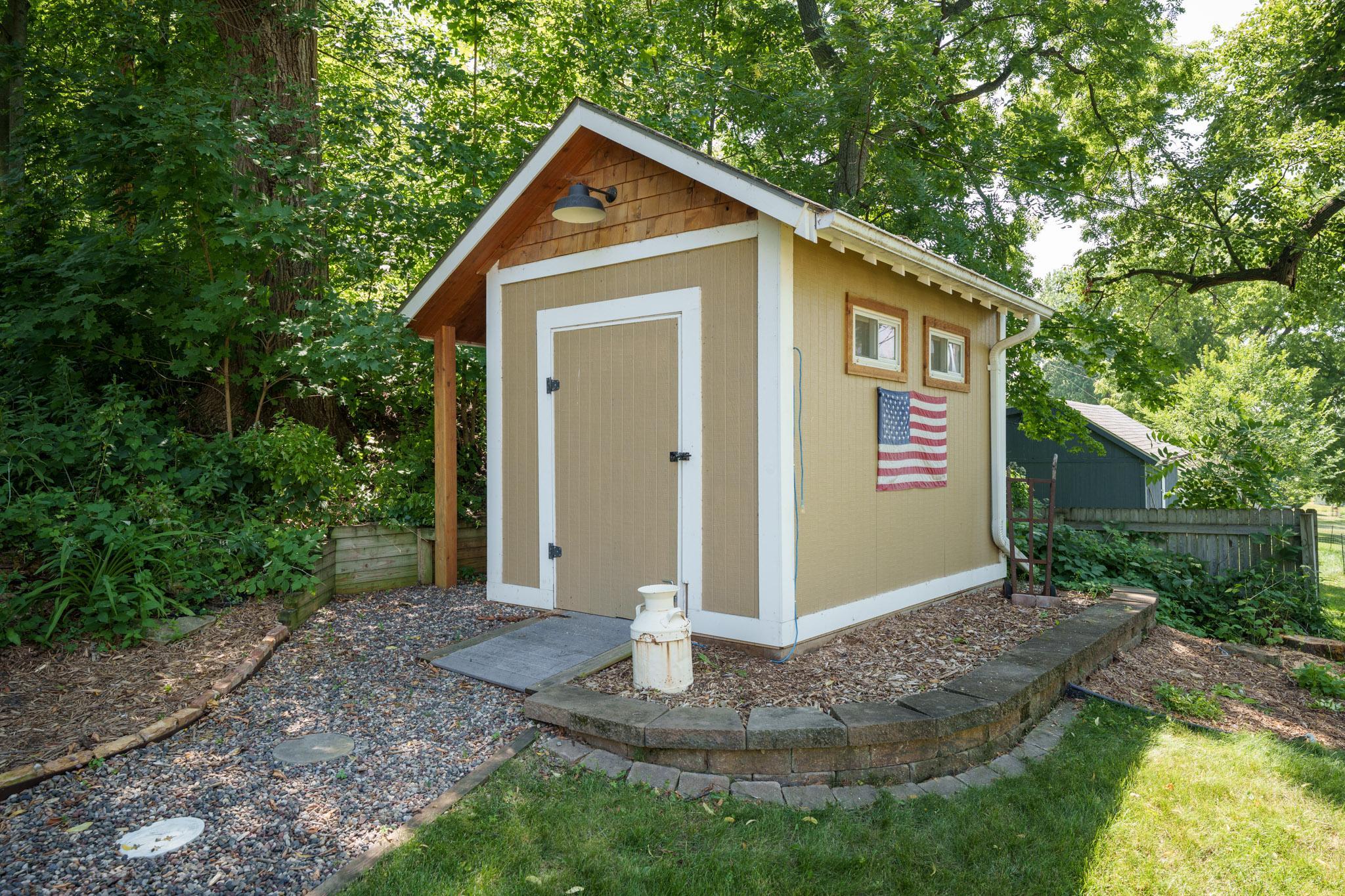 The storage shed is a cute accent to the yard and is located steps from the level with the firepit..
