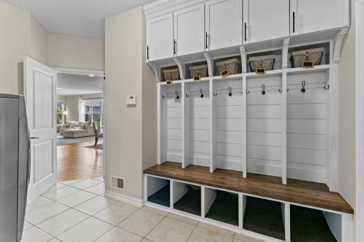 A convenient mudroom drop zone includes custom bench seating, built-in storage, LG washer and dryer, garage access. The washer features a small pedestal mini washing machine, essentially providing two washing machines!