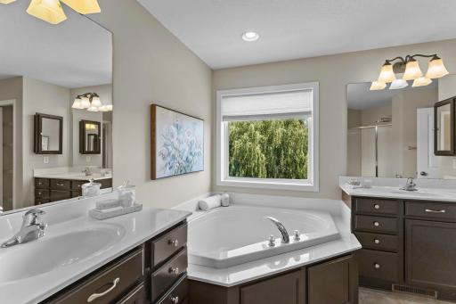 The ensuite bathroom features dual vanity areas, a walk-in shower, and soaking tub.