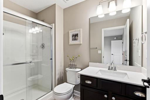 The 3/4 bath offers a glass door shower, crisp white counters, and warm finishes for guests and busy mornings.