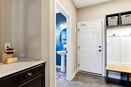 Just off the garage entry, a practical back hall links the powder room, mudroom storage, and kitchen in one smooth landing zone.