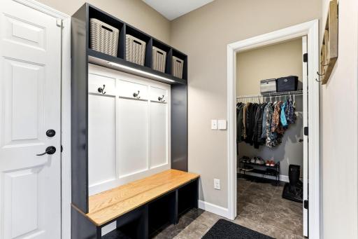 Custom locker-style built-ins with bench seating and cubbies, plus a walk-in closet for coats and gear.
