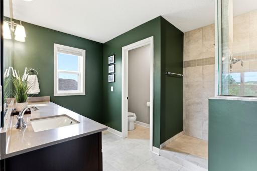 Rich green walls, a tiled walk-in shower, and a private water closet give the primary bath spa-level calm.