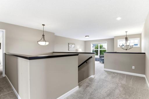 Black capped railings wrap the open stairwell, connecting loft, bedrooms, and landing in one bright hub.