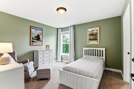 Sage green walls and vintage travel prints give this bedroom easygoing charm and a leafy view.