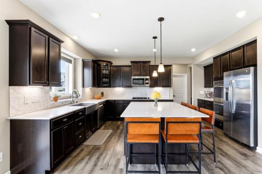 Espresso cabinetry, tiled backsplash, and stainless appliances surround island seating for the whole crew.