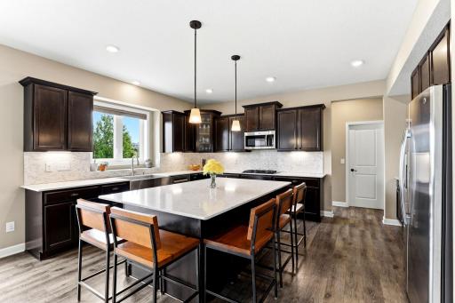 Quartz counters and an oversized island anchor the kitchen, with pendant lighting adding a warm evening glow.