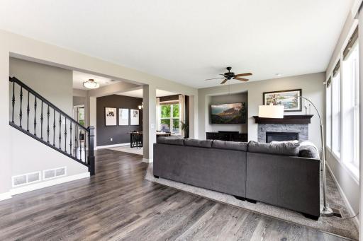 Wide-plank flooring and a wrought iron staircase carry a fresh, modern palette across the main level.