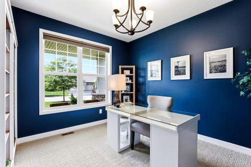 Deep blue walls, a classic chandelier, and a bright front-facing window make the main floor office a room you actually want to work in.