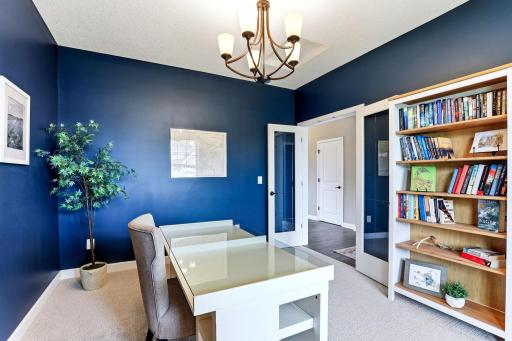 Glass French doors and a bold navy palette make the front office equal parts library and workspace.