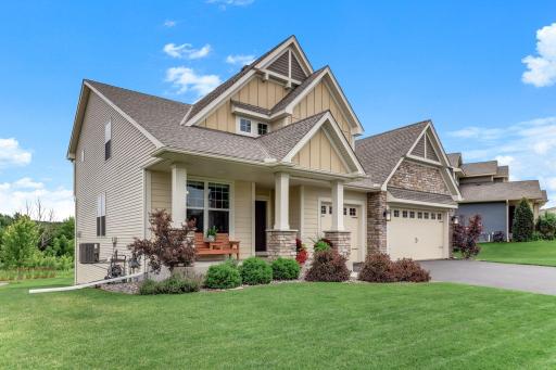 The covered front porch invites slow mornings, with stone-wrapped pillars and perennial beds adding warmth at the entry.