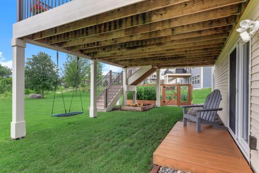Under the deck, a shaded patio and hanging swing offer a cool retreat on warm afternoons.
