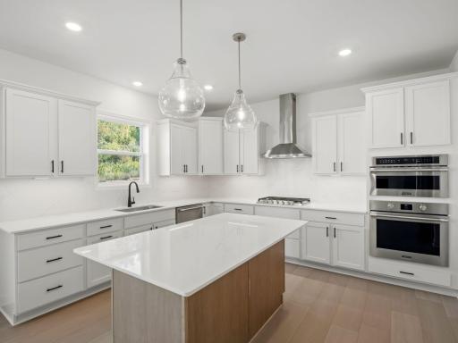 This stylish kitchen showcases a large center island, Shaker-style cabinetry, and brand-new stainless-steel appliances.