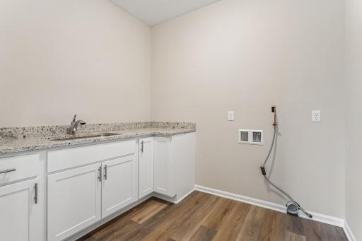 A surprisingly large laundry room with sink, granit countertops and cabinetry. So much room to add shelving or upper cabinets for storage and organization!