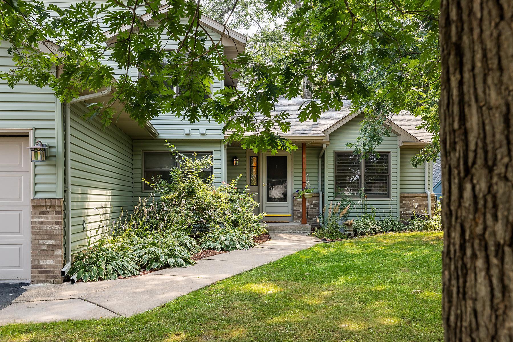 Mature lot with oak trees and perennials, curved walkway and covered porch entry.